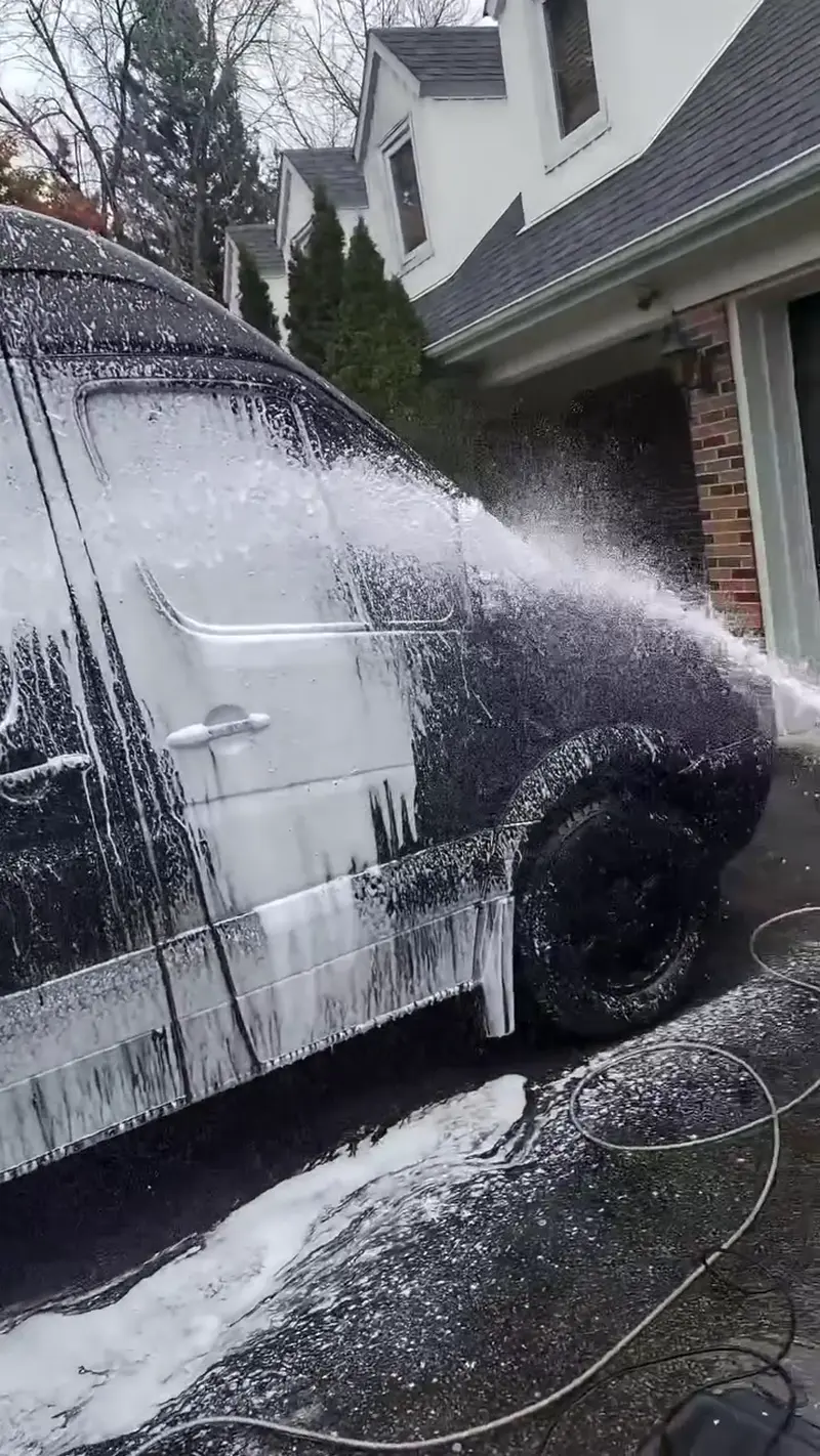 Mobile detailing team foam washing a white van